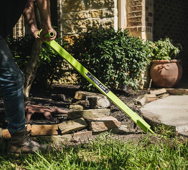 man using the Strongarm to level a sidewalk